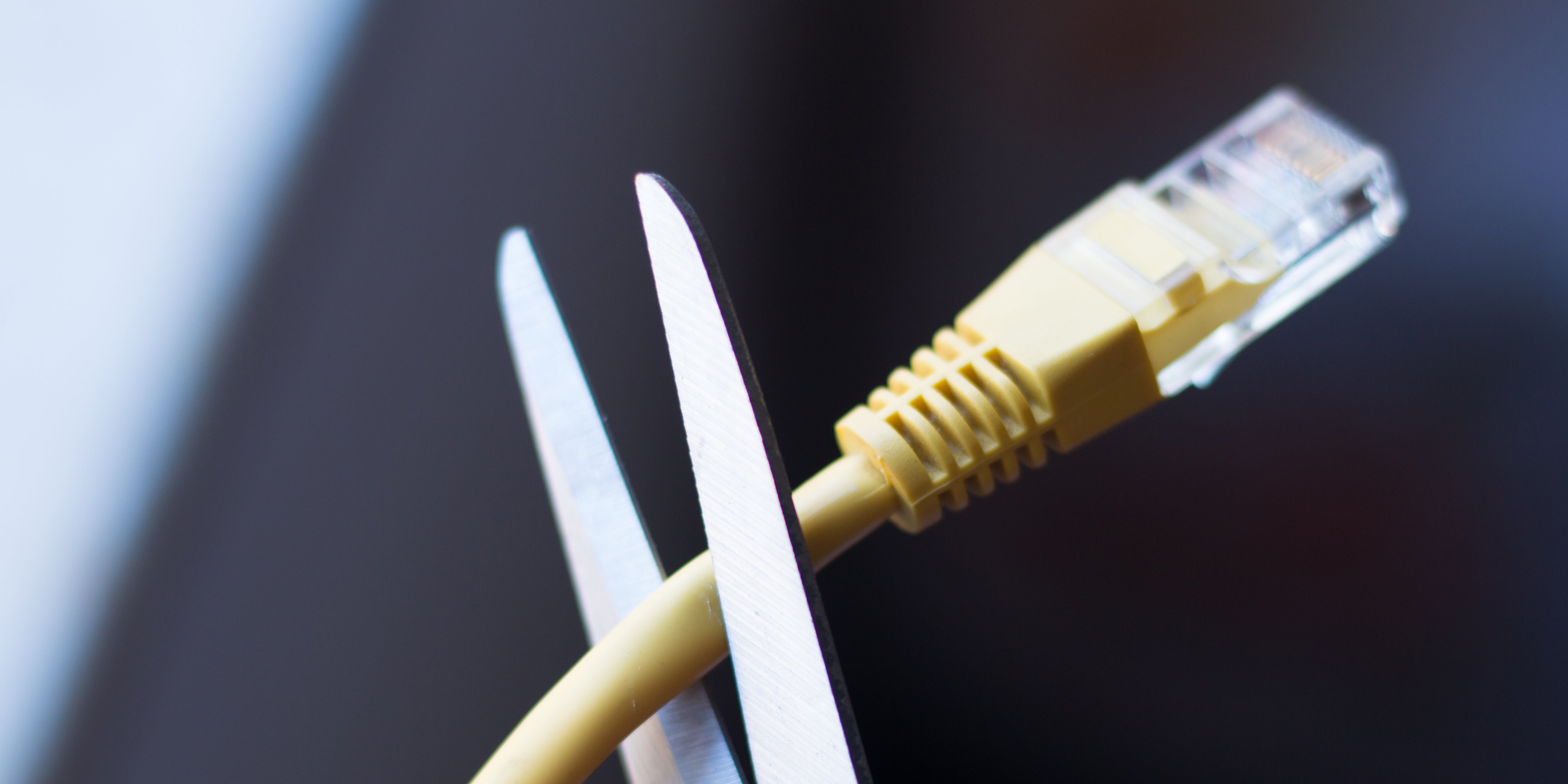 An ethernet cord being cut with scissors.