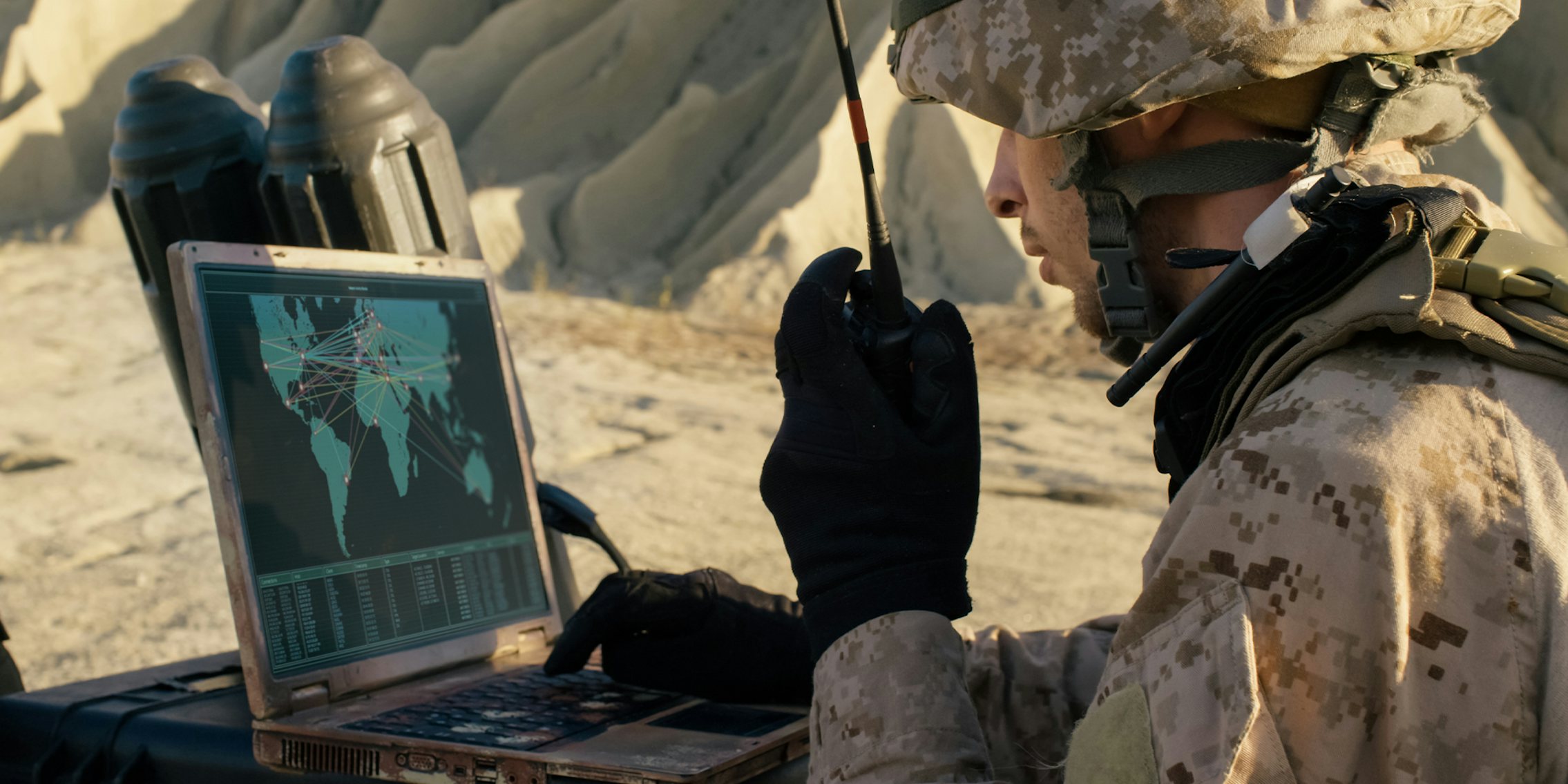 Soldier is Using Laptop Computer and Radio for Communication During Military Operation in the Desert.