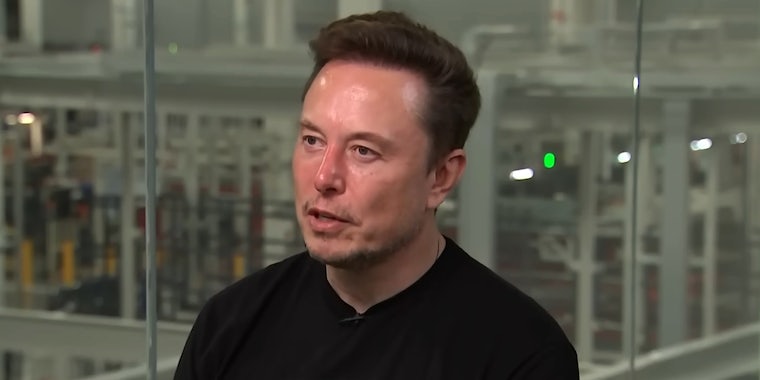 Elon Musk speaking in front of glass wall