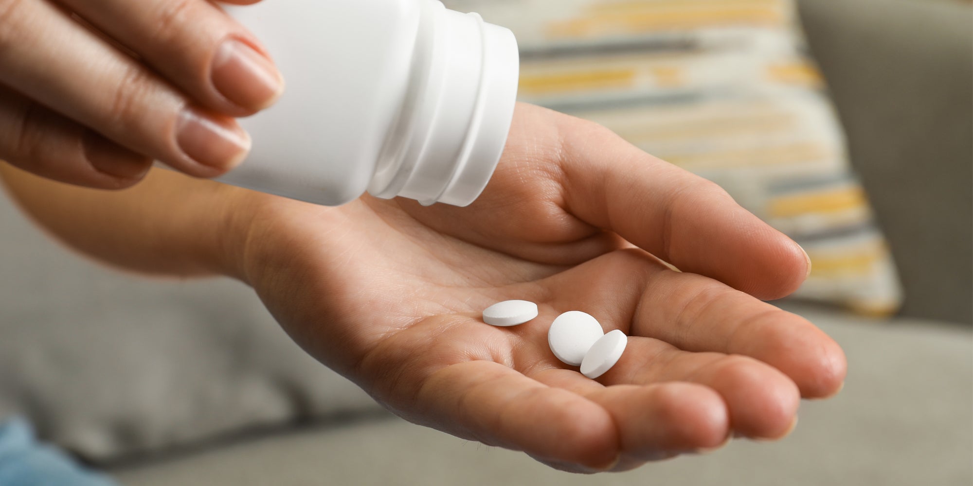 hand pouring pills from bottle into other hand