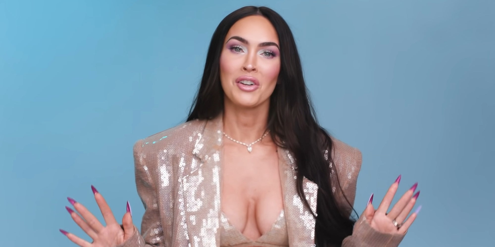 Megan Fox speaking in front of blue background