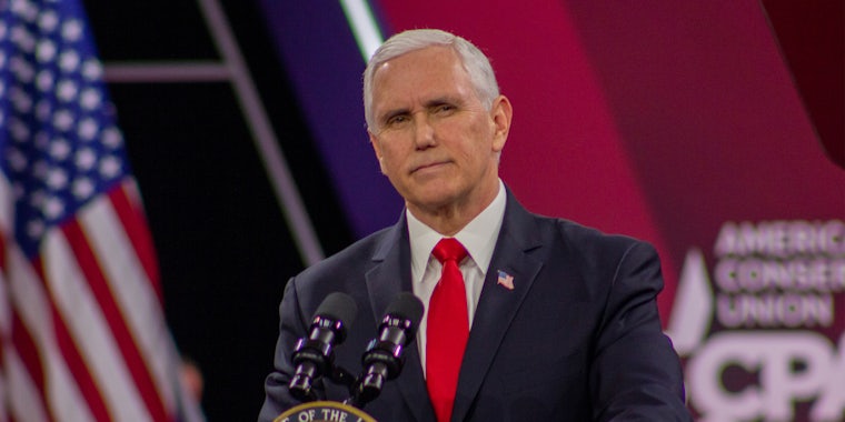 Mike Pence with microphone in front of red and American flag background