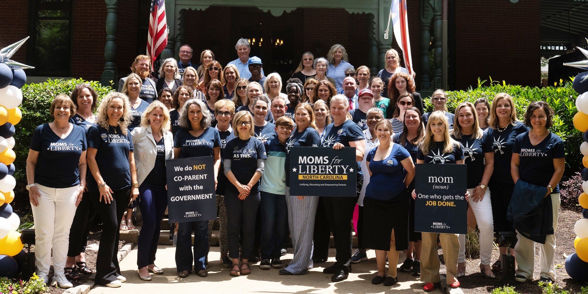 Moms for Liberty group standing together outside with signs