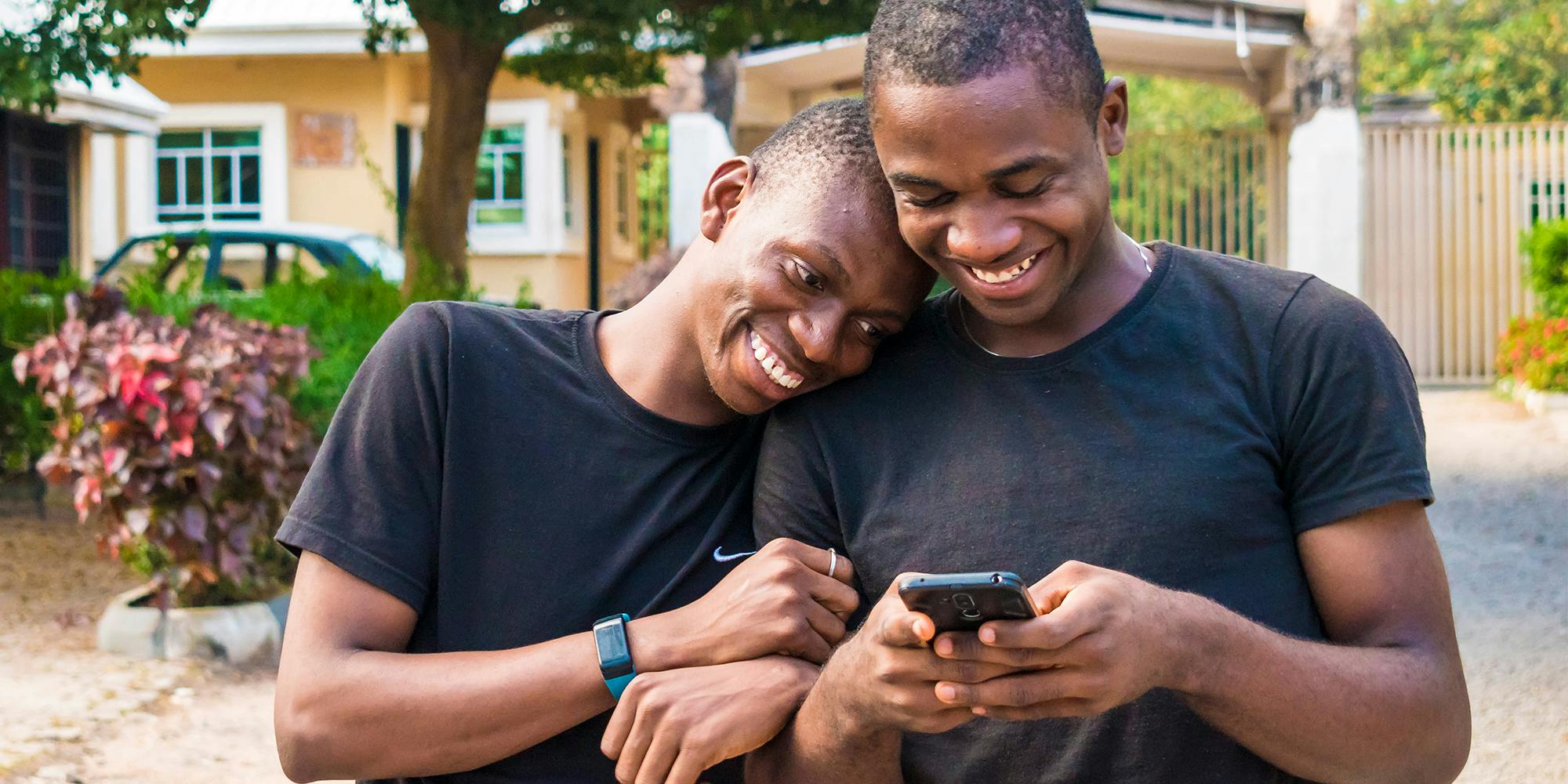 Two men smiling while looking at a phone