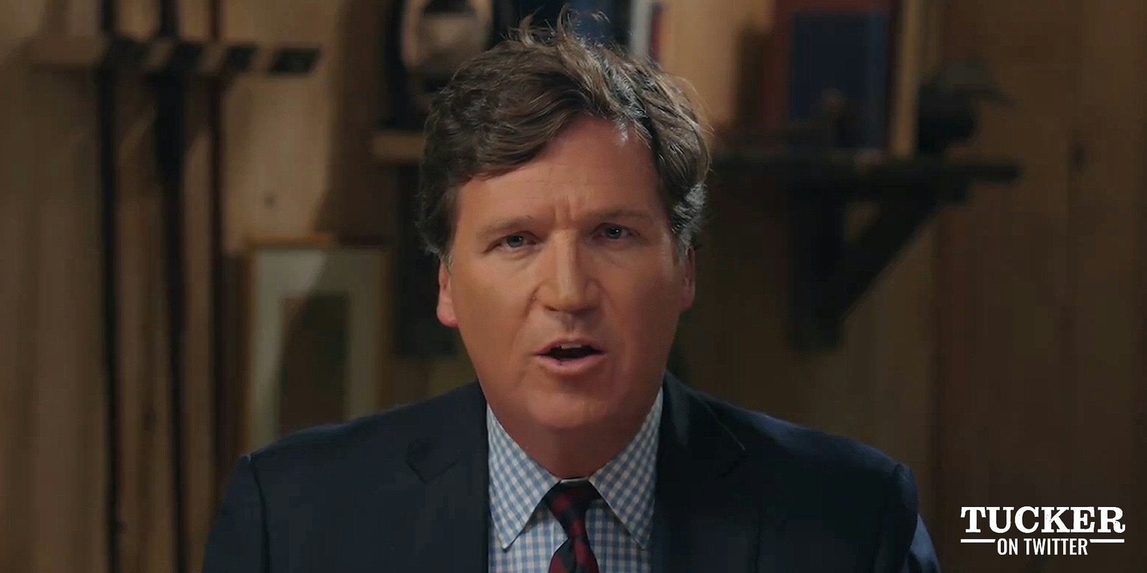 Tucker Carlson speaking in front of blurry brown background during Tucker On Twitter Ep. 1