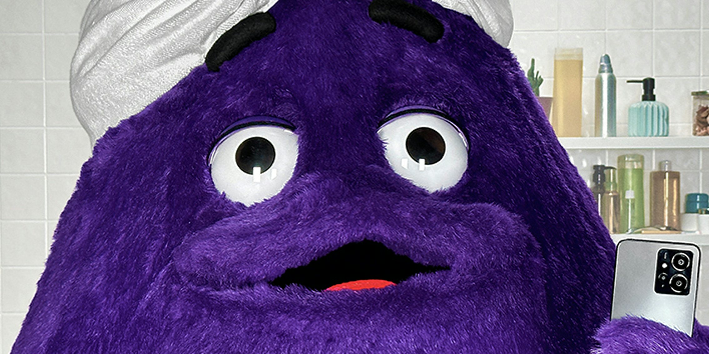 McDonald's character Grimace posing in mirror selfie in bathroom with towel wrapped on head
