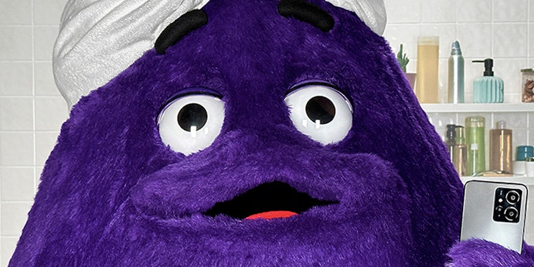 McDonald's character Grimace posing in mirror selfie in bathroom with towel wrapped on head
