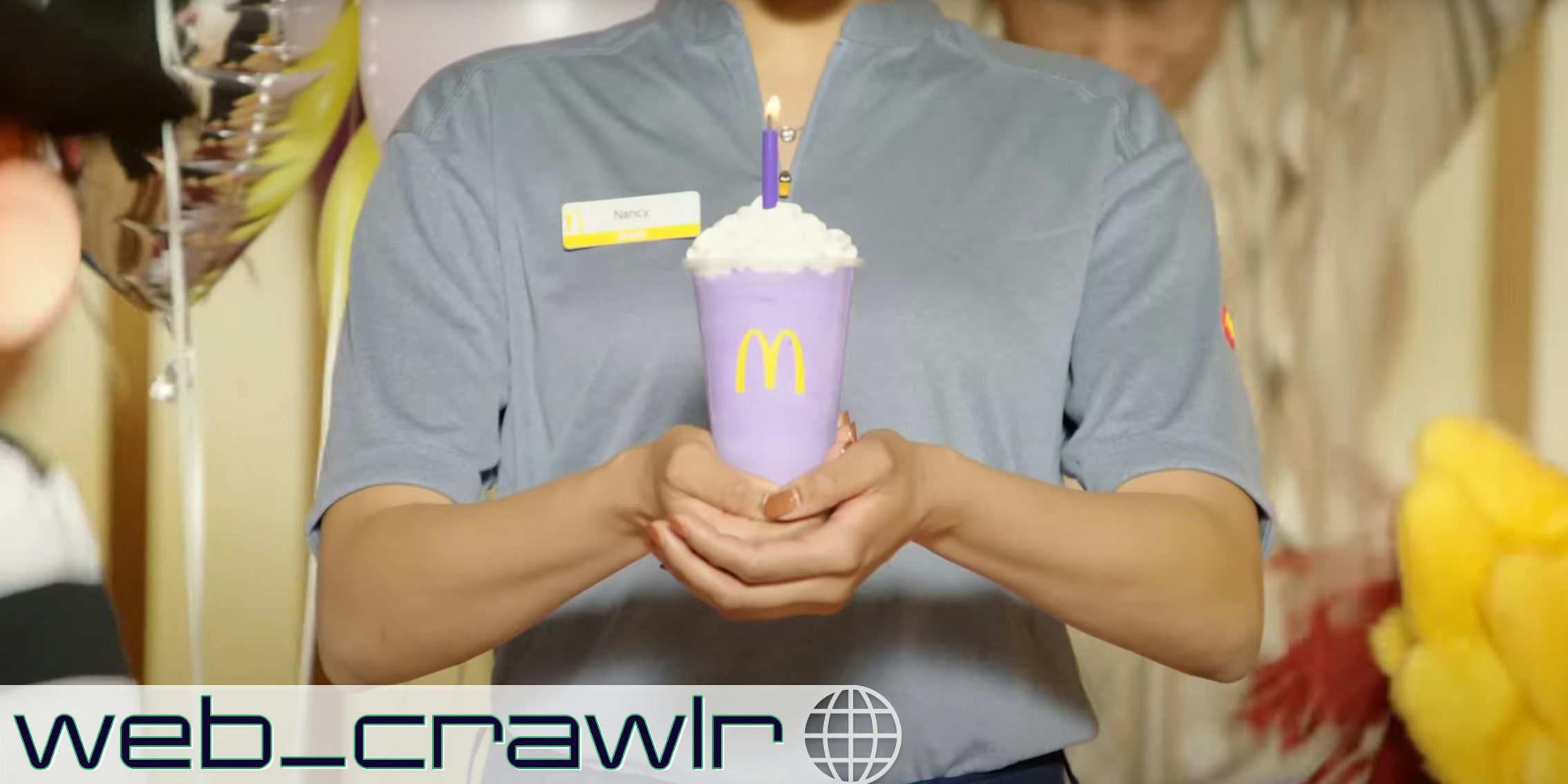 A McDonald's employee holding a Grimace shake. The Daily Dot newsletter web_crawlr logo is in the bottom left corner.
