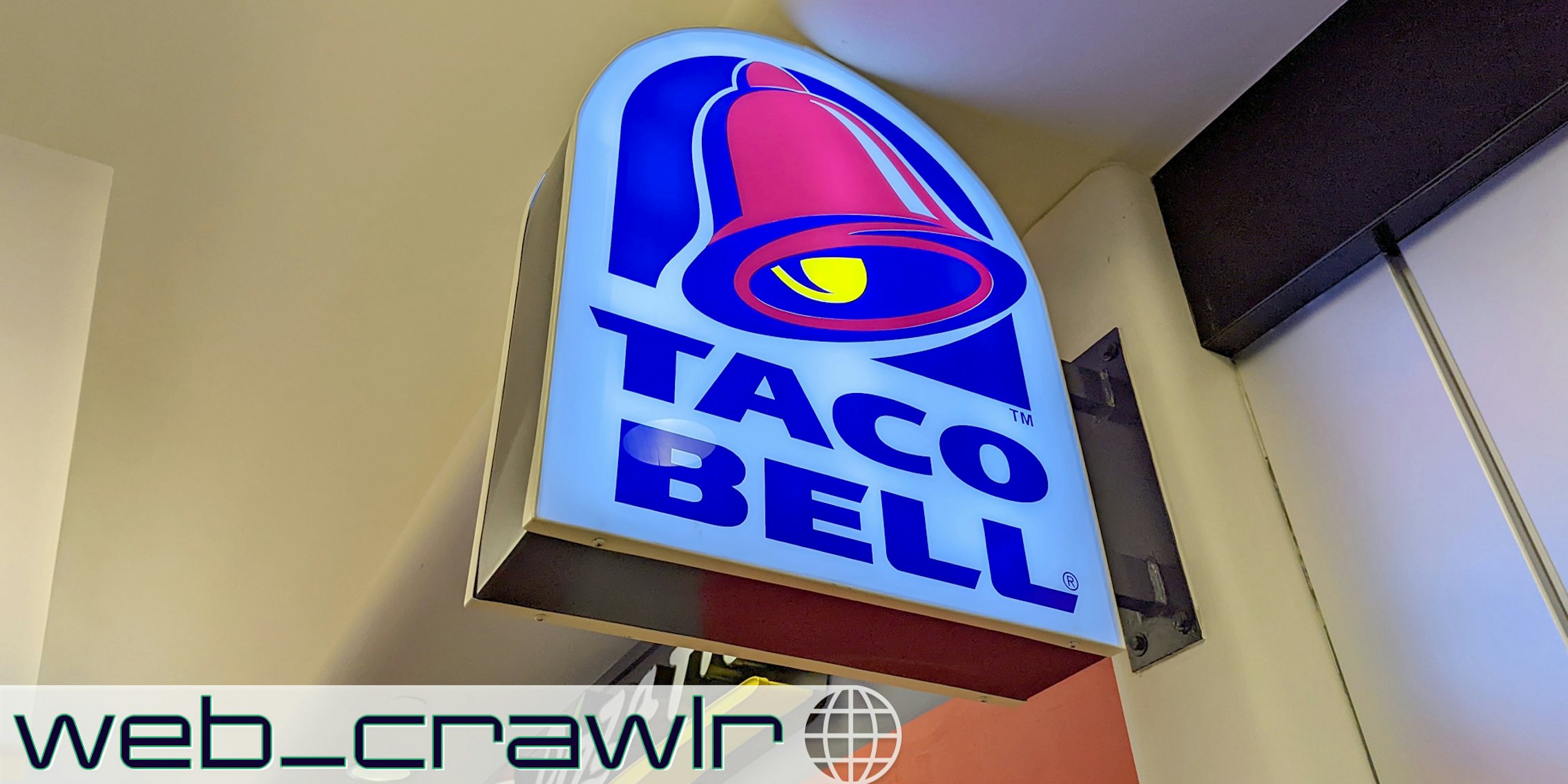 A Taco Bell sign. The Daily Dot newsletter web_crawlr logo is in the bottom left corner.