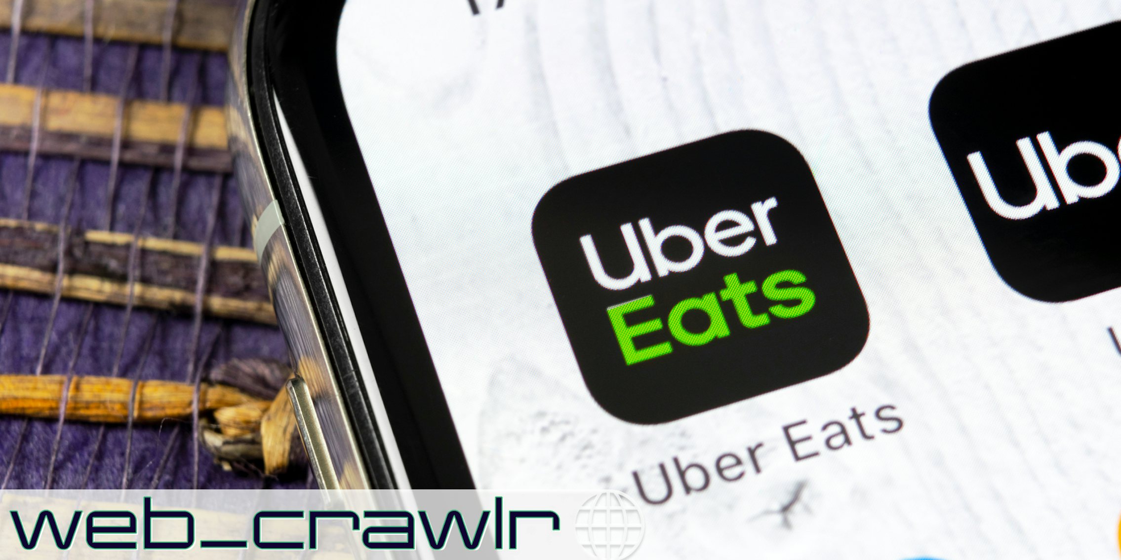 A phone showing an Uber Eats app. The Daily Dot newsletter web_crawlr logo is in the bottom left corner.