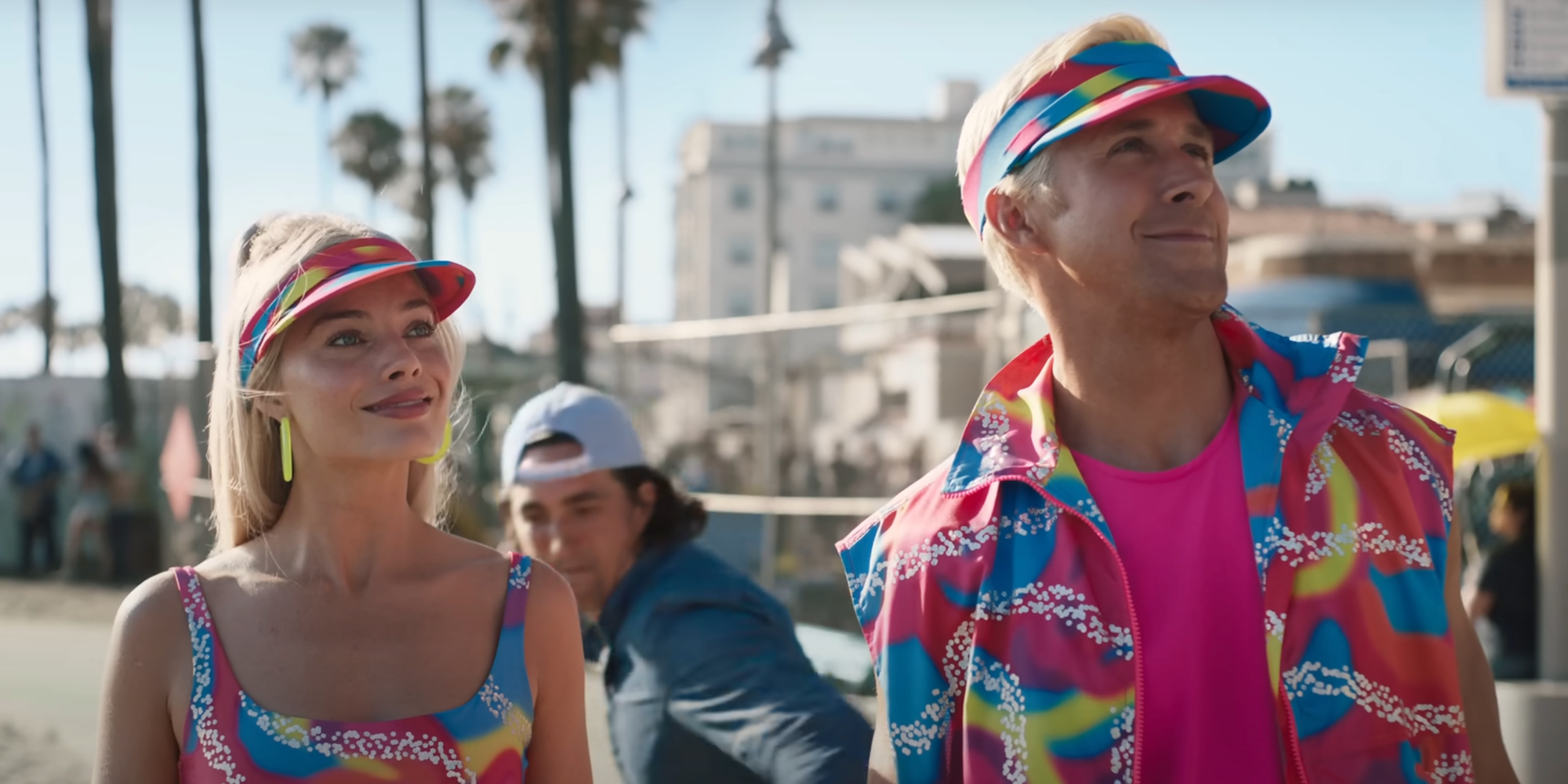 margot robbie and ryan gosling in neon rolling skating outfits, looking up and smiling in Barbie.