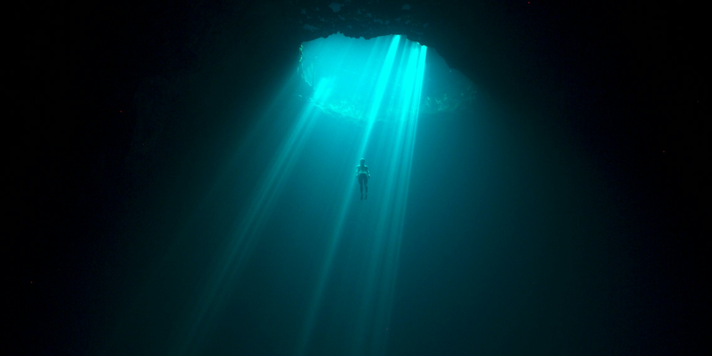 a wide shot of someone in the arch, a deadly but popular spot for free divers, in the deepest breath