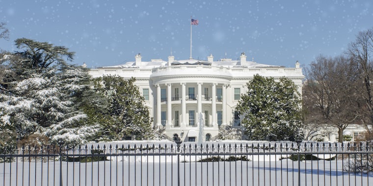 White House and grounds covered with snow with snow overlay on blue sky