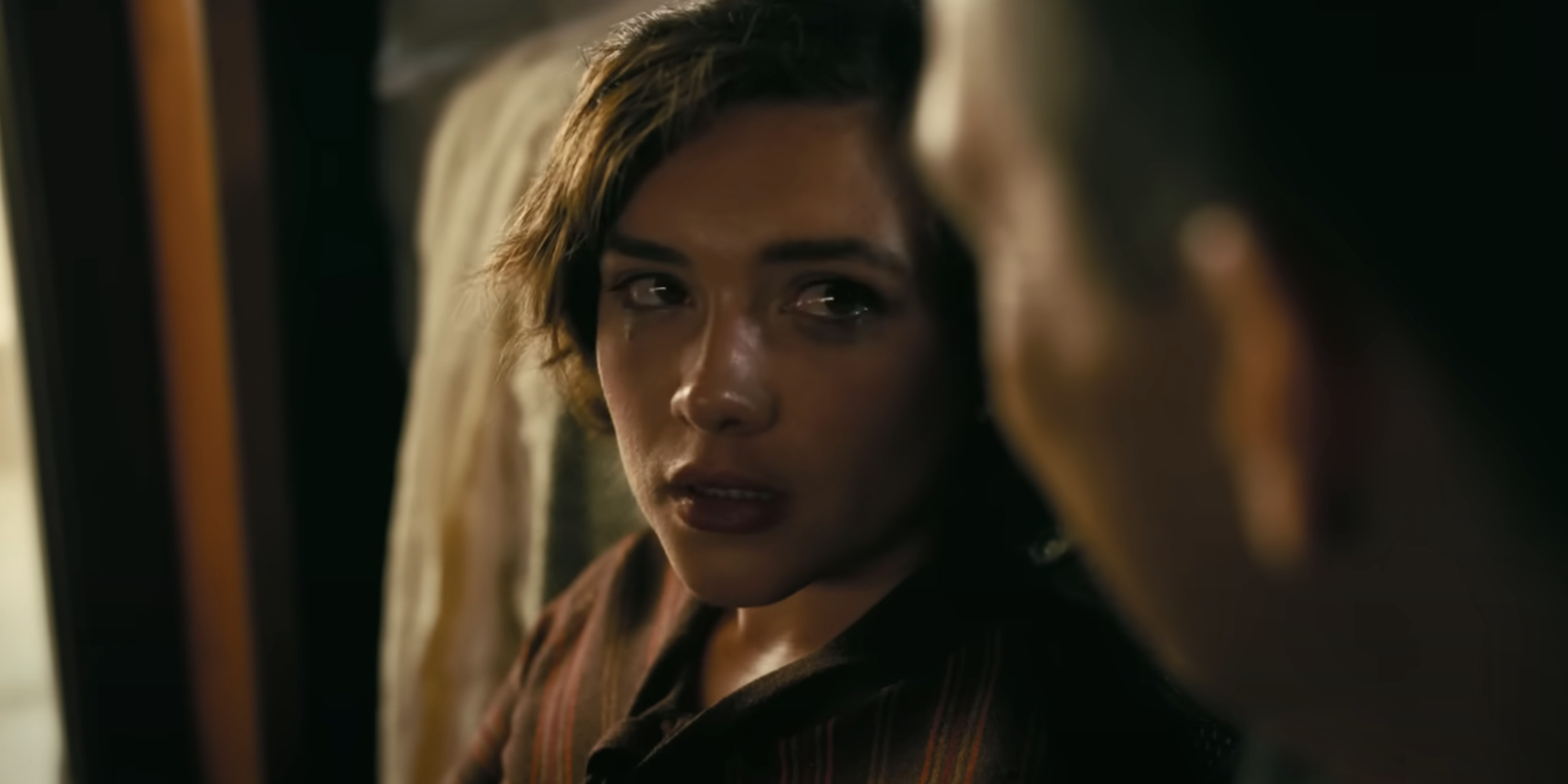 Florence Pugh looking at the camera and crying in the movie Oppenheimer. She plays Jean Tatlock.