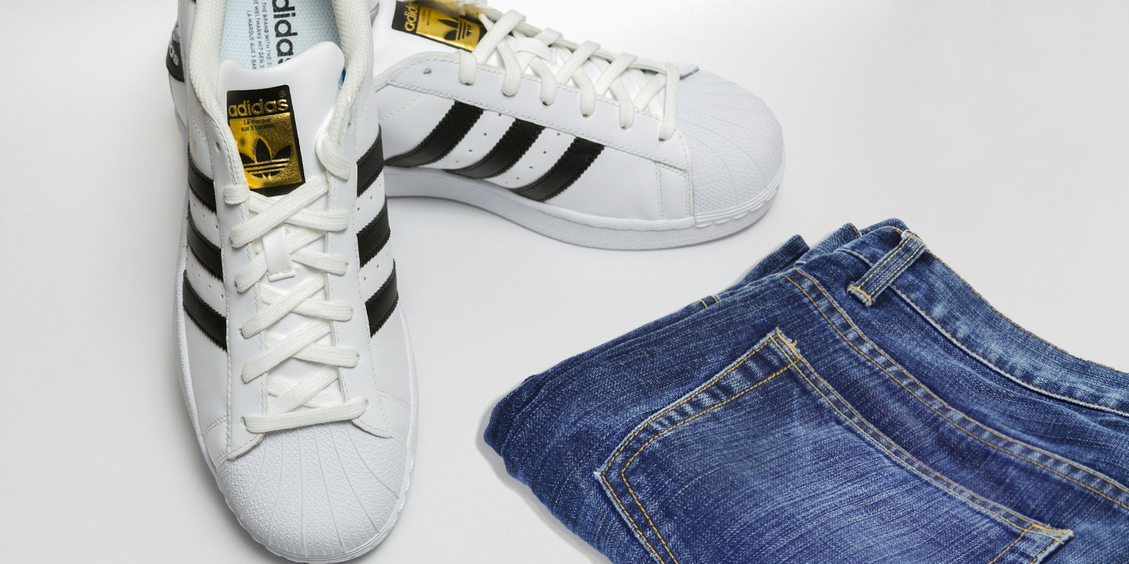 Addidas sneakers on white surface with jean shorts folded