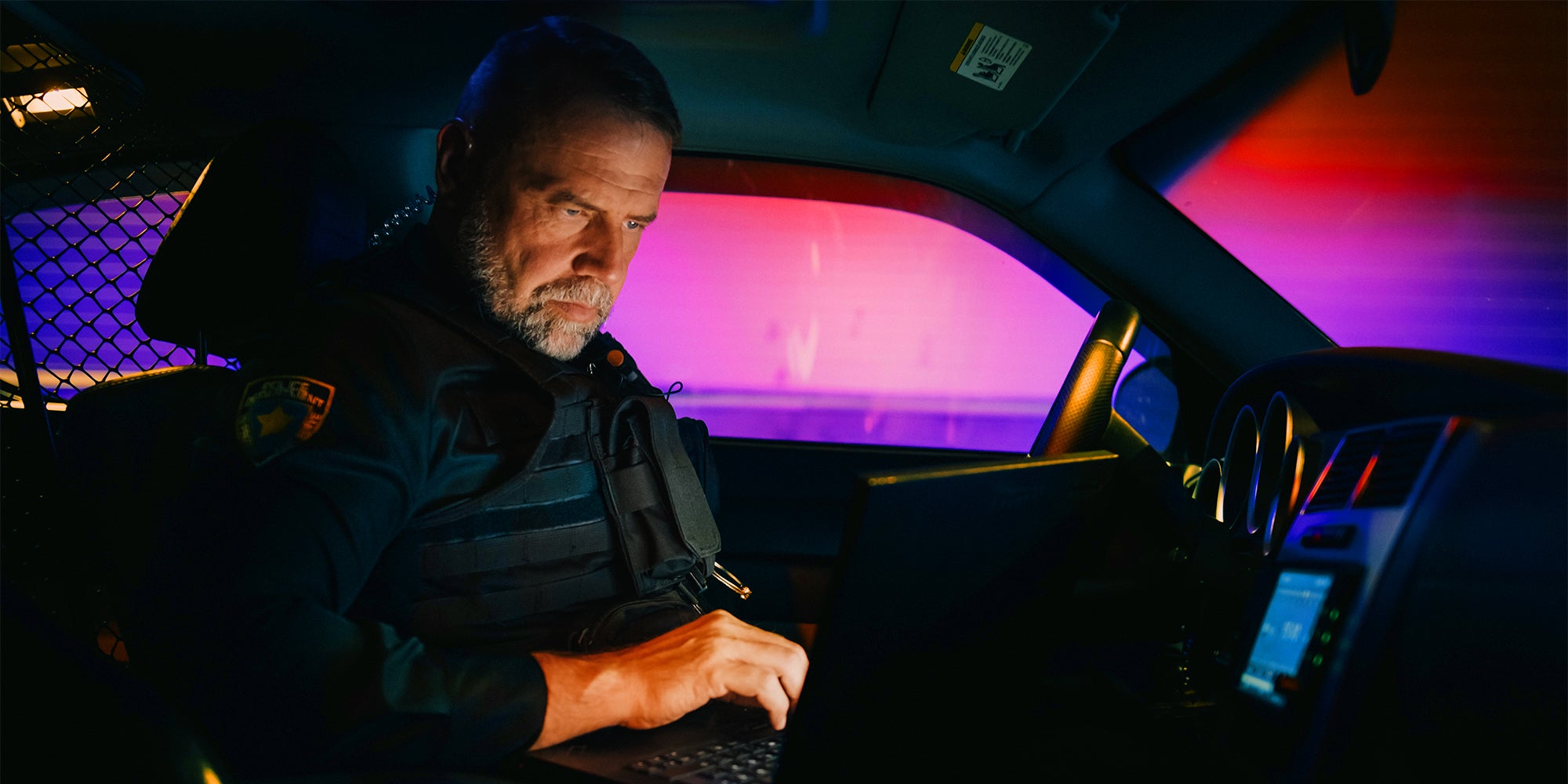 police officer in car using laptop