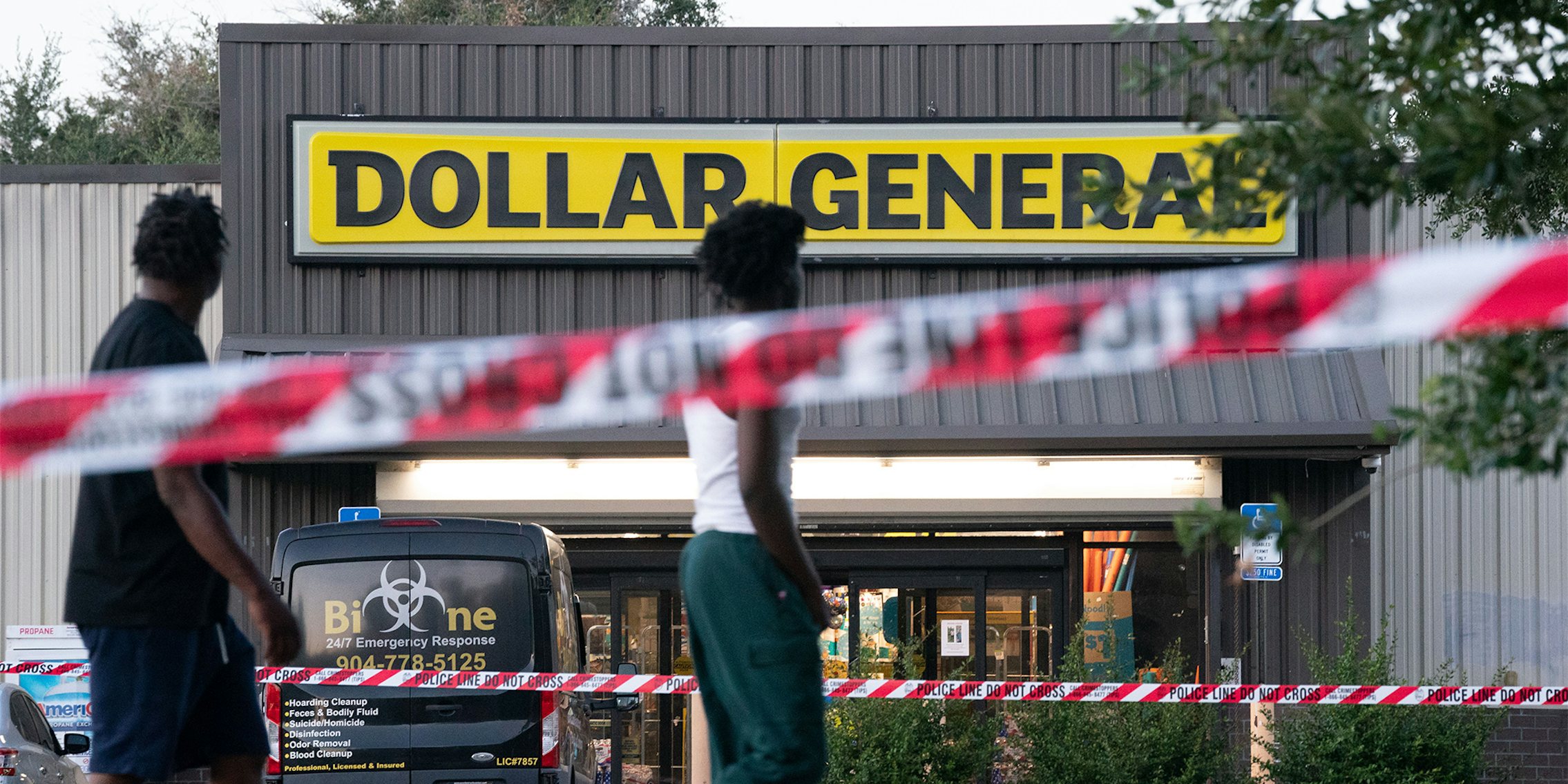 Pedestrians walk past a Dollar General store with police tape around