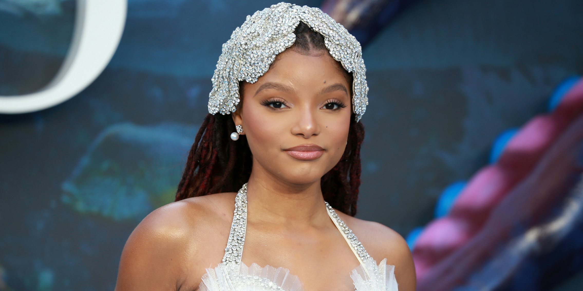 Halle Bailey in front of blue purple and green background