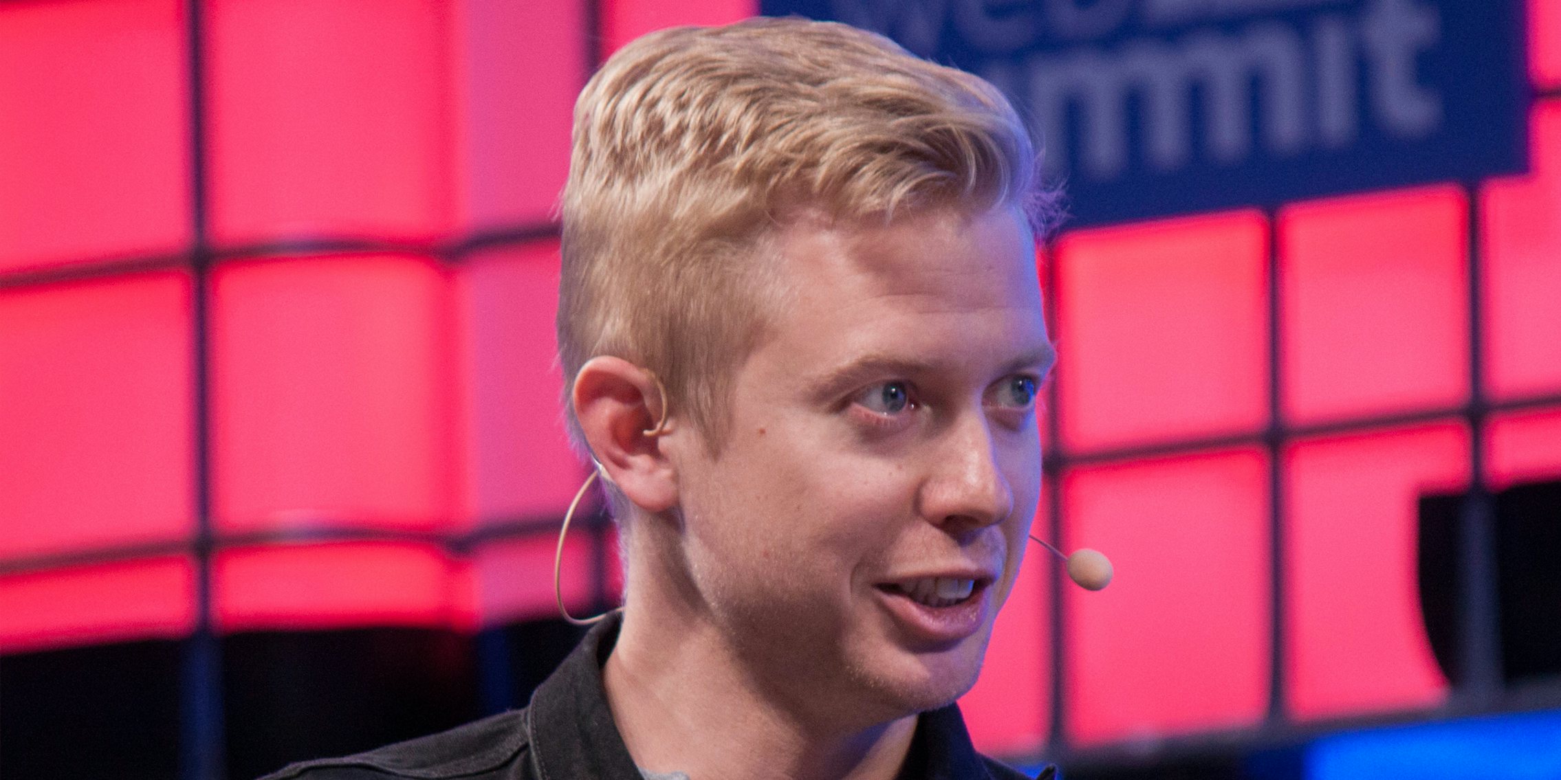 Steve Huffman speaking in front of pink and blue background