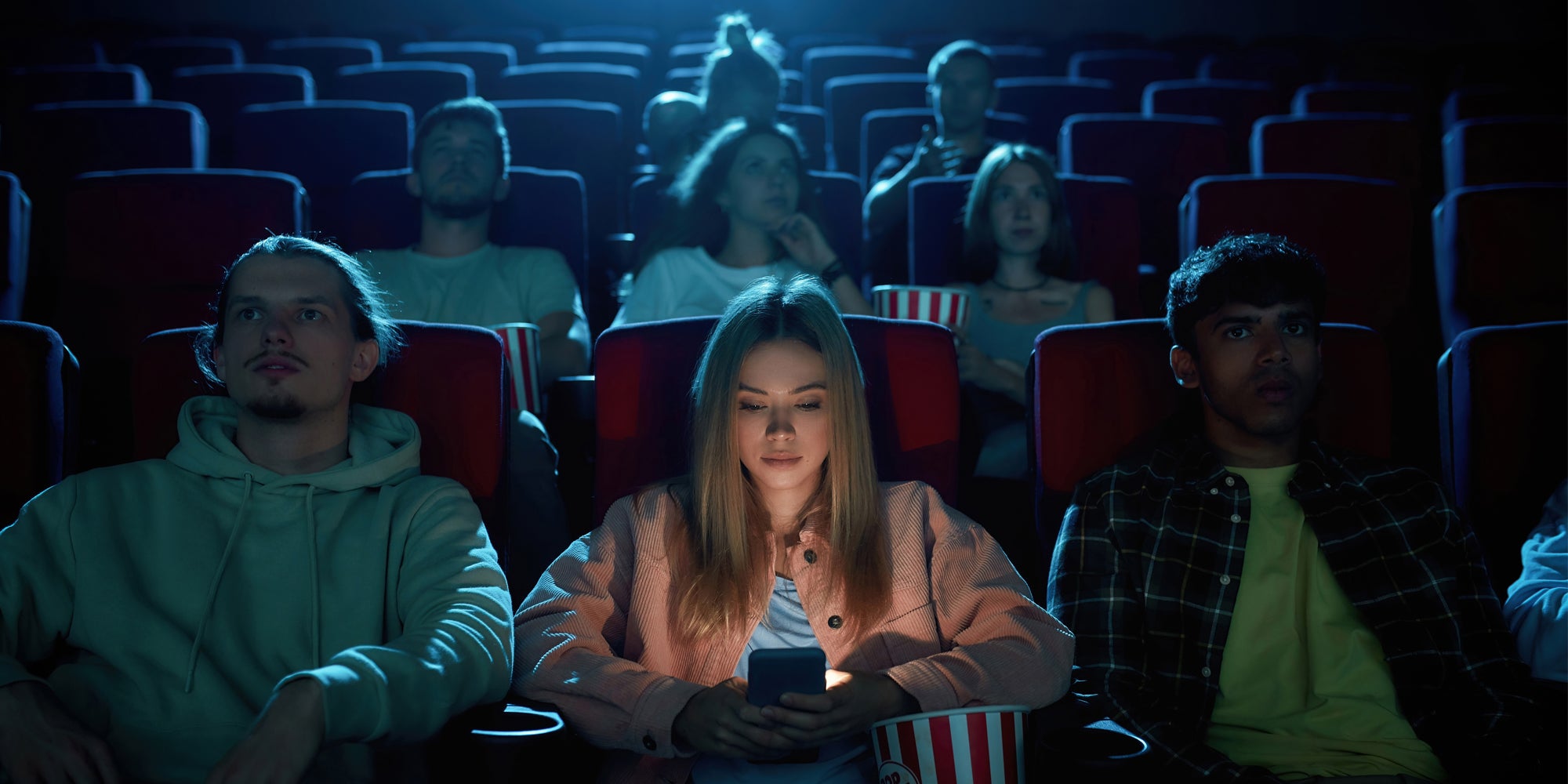 A person using a phone in a movie theater.