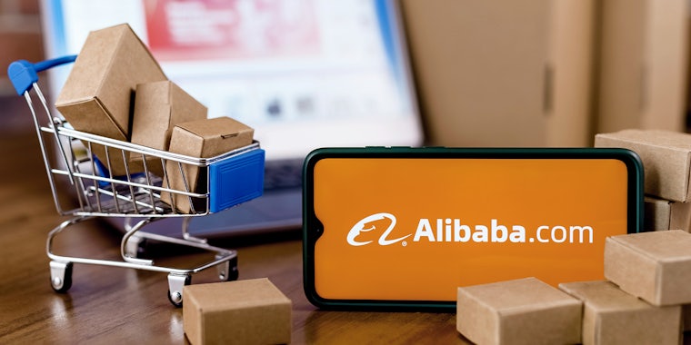 Alibaba Group is an Chinese e-commerce and online retail company. Smartphone with Alibaba Group logo on the screen, shopping cart and laptop.