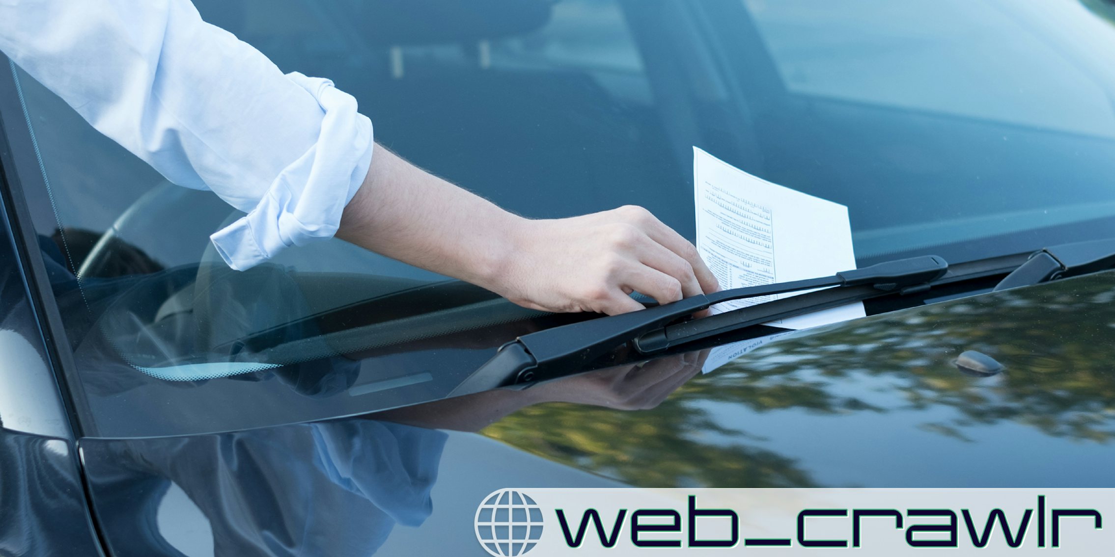 A person grabbing a parking ticket under a windshield wiper. The Daily Dot newsletter web_crawlr logo is in the bottom right corner.