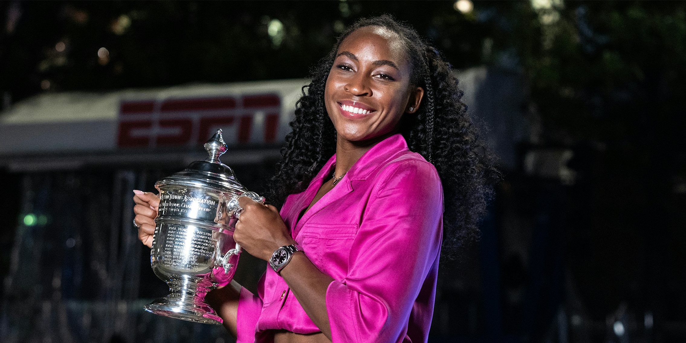 Coco Gauff winner of women's championship of US Open poses with trophy in front of fountain at Billie Jean King Tennis Center in New York on September 9, 2023