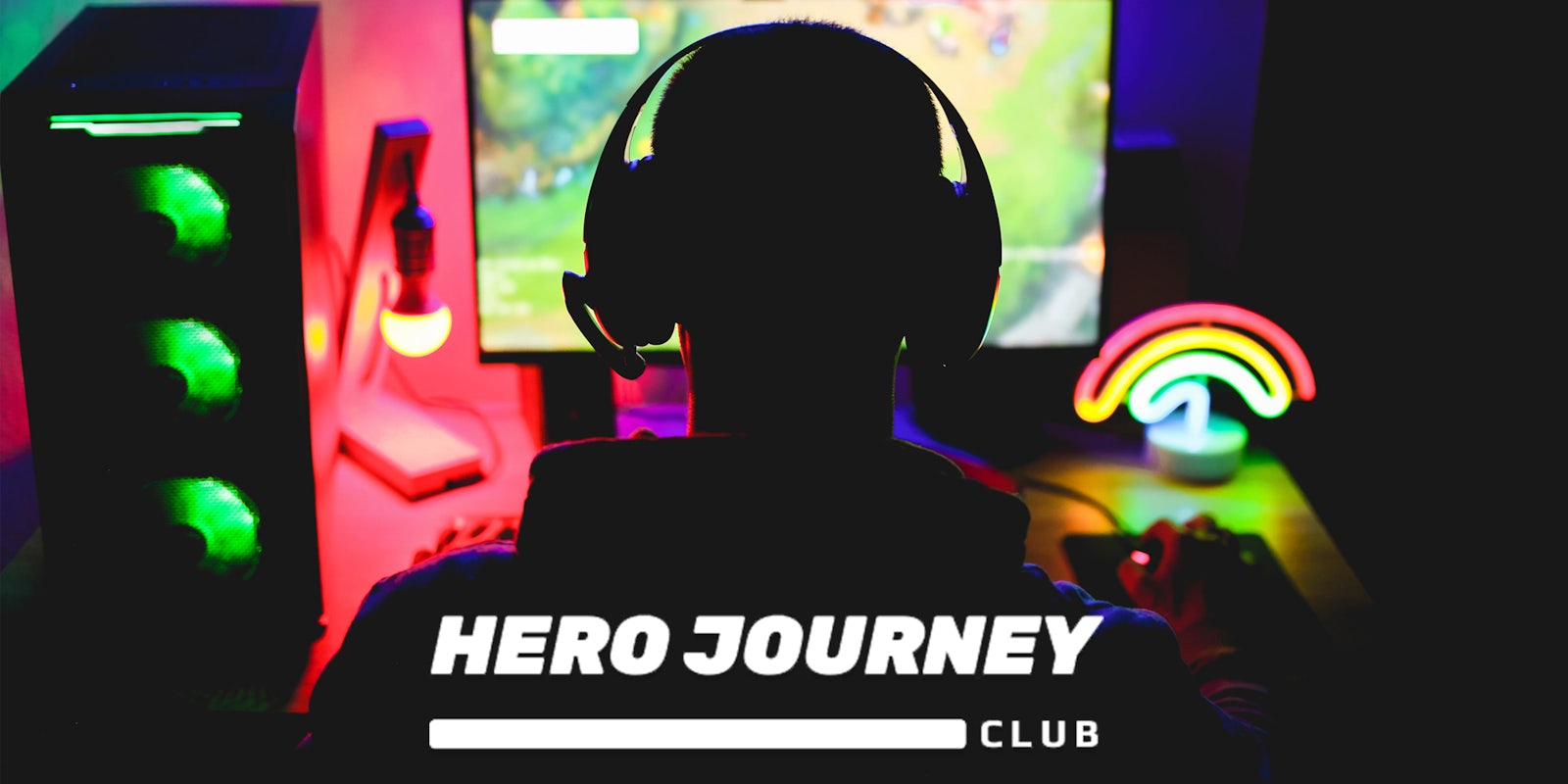 Gamer at desk setup with Hero Journey Club logo at bottom
