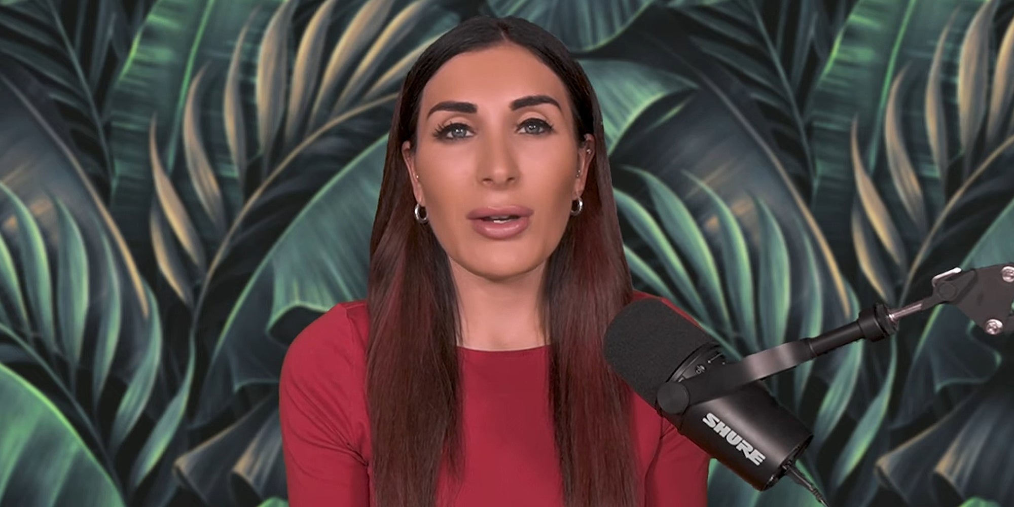 Laura Loomer speaking into microphone in front of leaves background