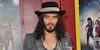 Russel Brand in front of red background