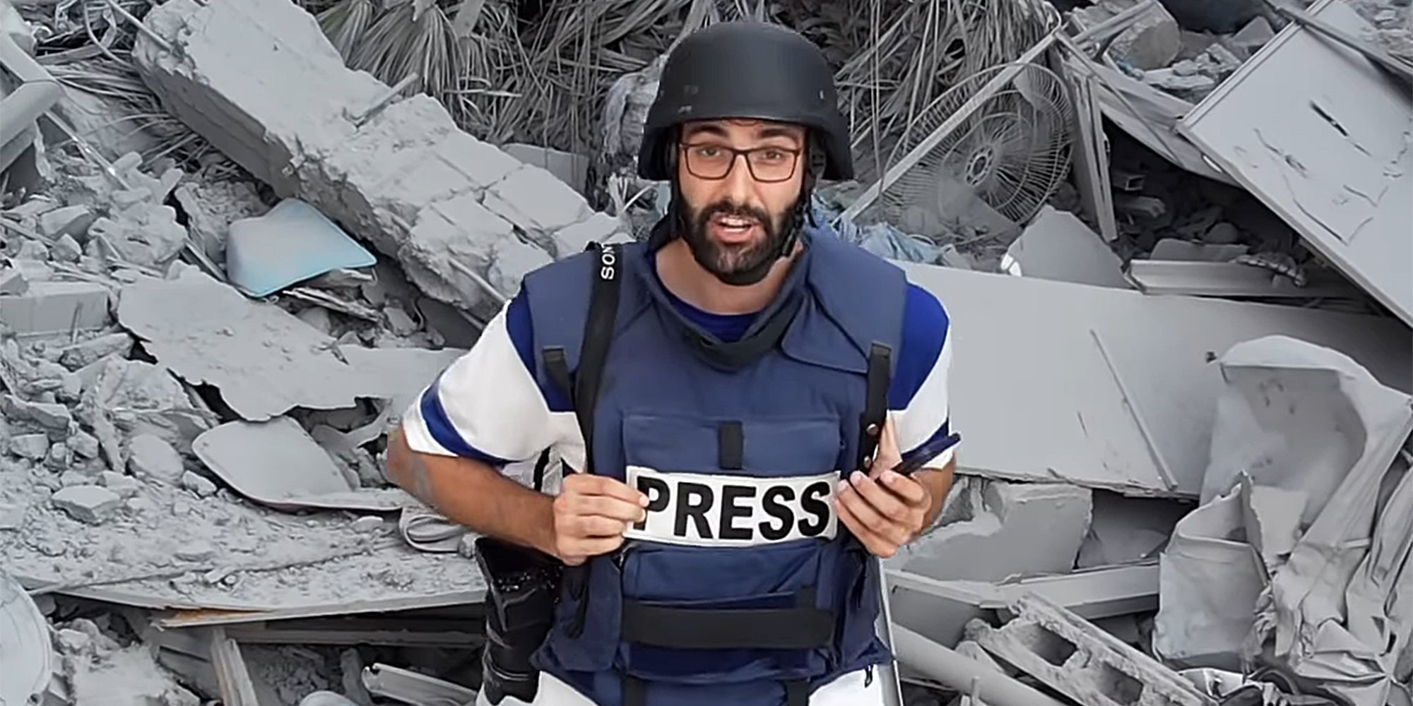 Motaz Azaiza wearing Press flak vest and helmet in ruins