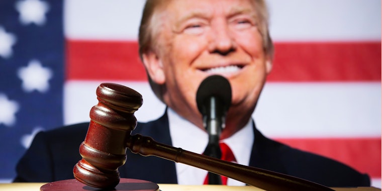 wooden gavel in front of Donald Trump in front of American flag