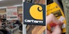 Clearance isle; Carhartt sign logo; person peeling off pricing tag