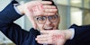 Happy man in eyeglasses showing word weekend written on his palms for funny friday memes story