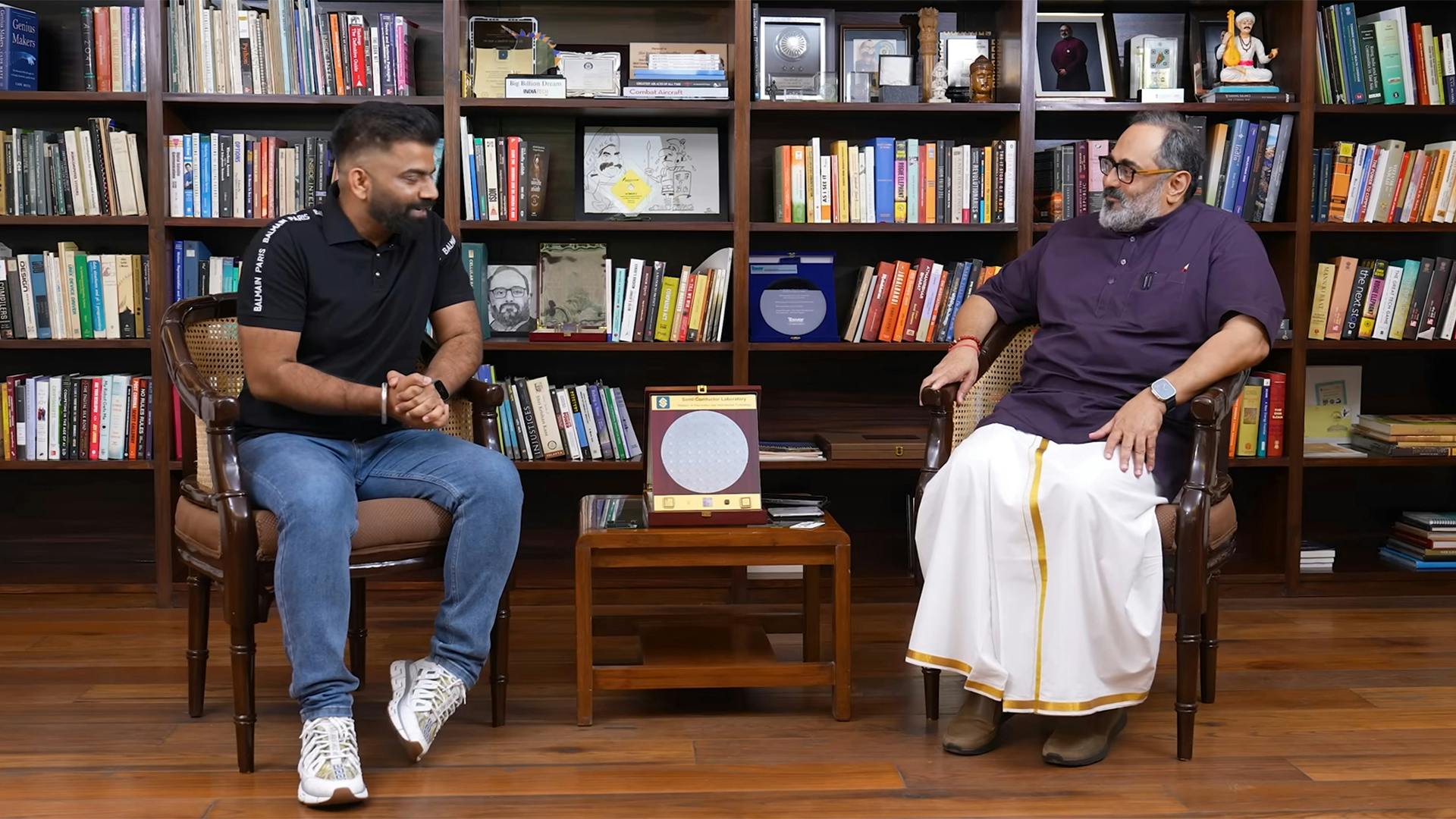 two men talking in front of bookshelves