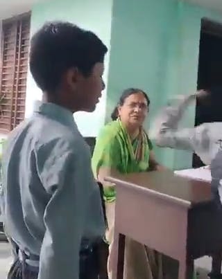 teacher watches as one student slaps another