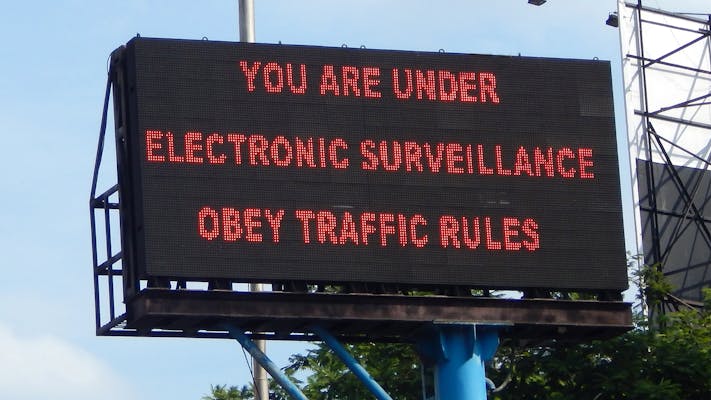 traffic sign reads "You are under electronic surveillance obey traffic rules"