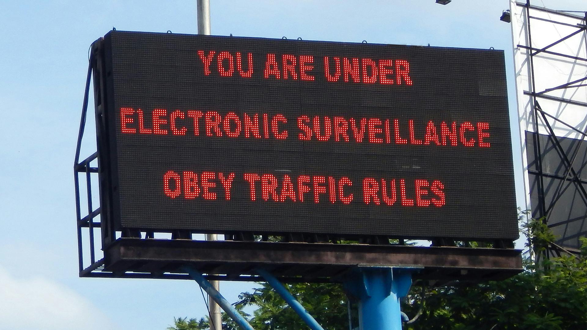 traffic sign reads 'You are under electronic surveillance obey traffic rules'
