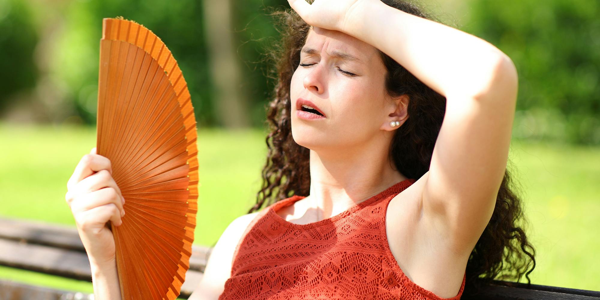 Woman fanning herself to illustrate sweating memes story