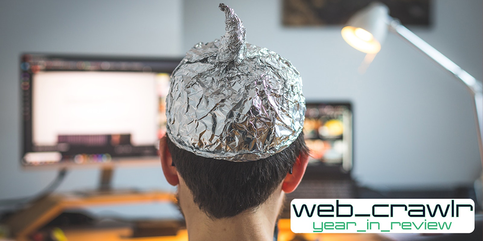 man with tin foil conspiracy cap on head at desk with web_crawlr year_in_review logo at bottom right corner