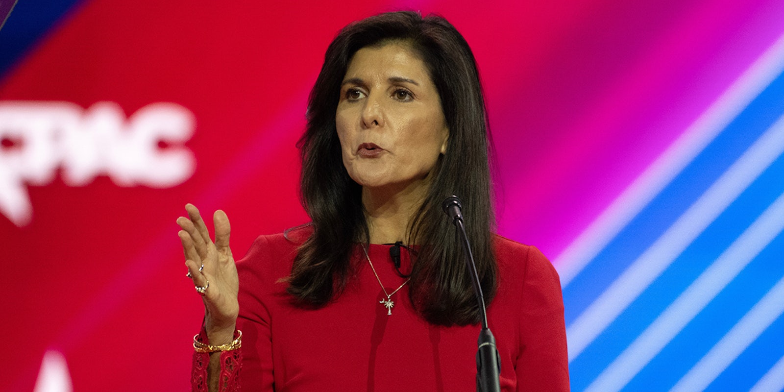 Nikki Haley speaking in front of red pink and blue background