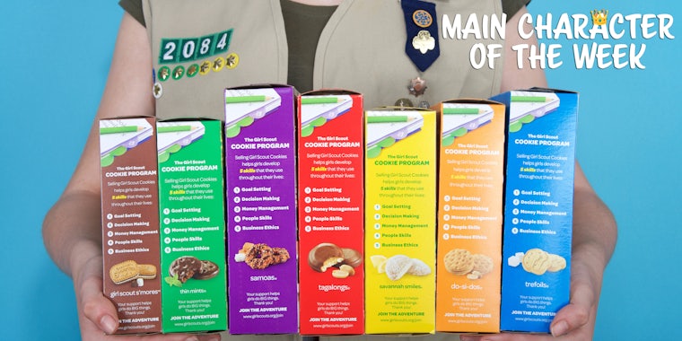 A person holding numerous Girl Scout cookies. In the top right corner is text in a web_crawlr font that says 'Main Character of the Week'