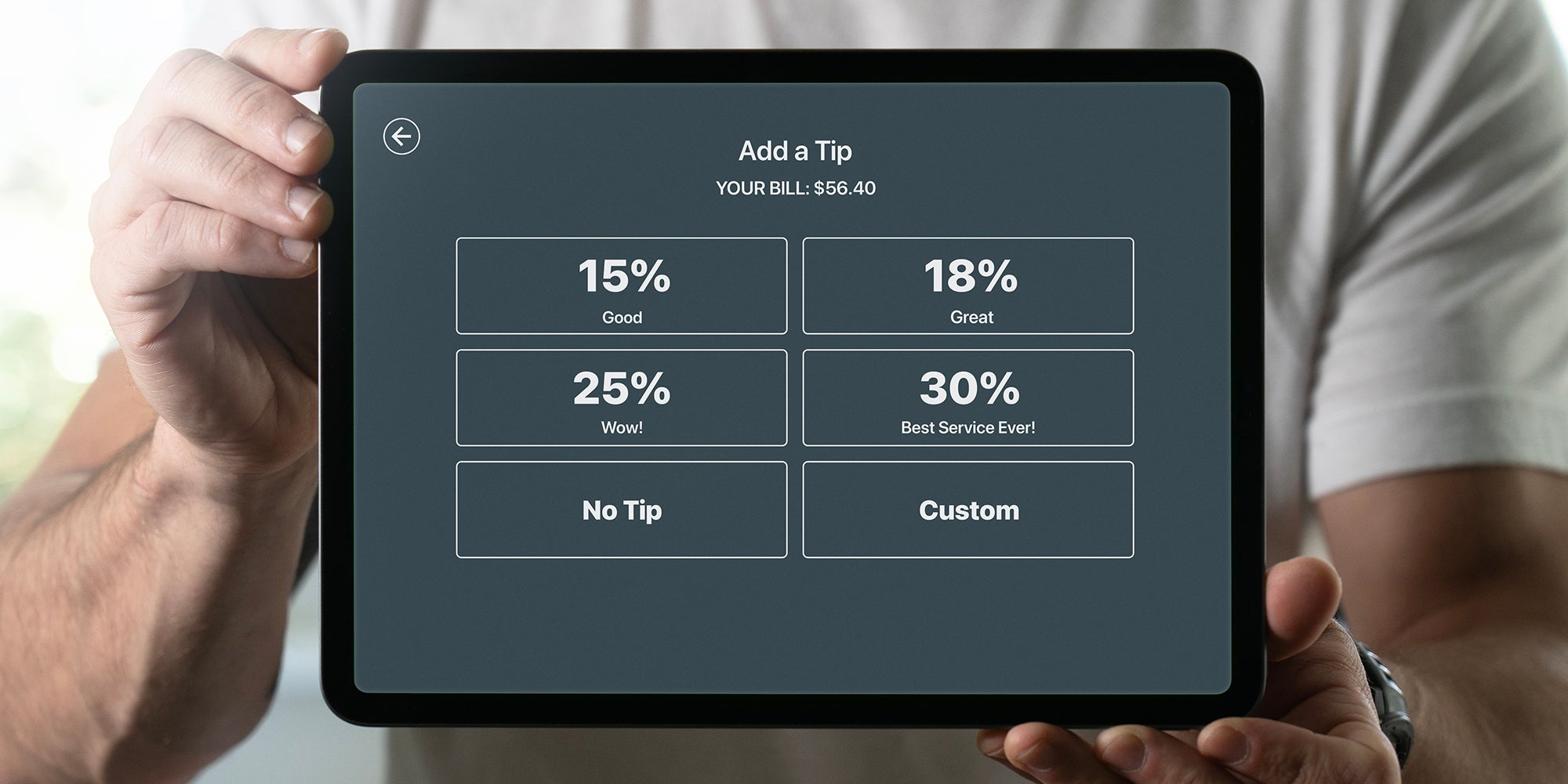 Man holding a tablet with tipping screen inside a restaurant