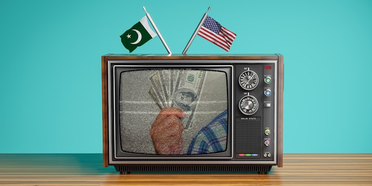 hand holding $100 bills on a television with static - Pakistani and American flags attached to antennae