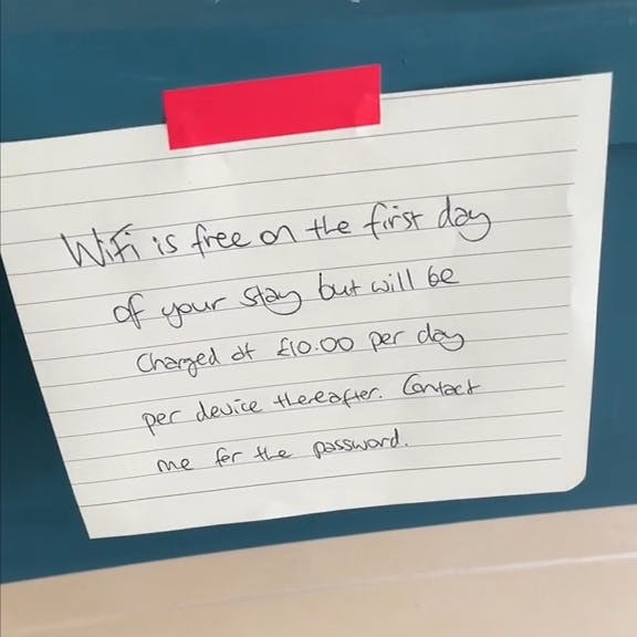 Handwritten note that reads 'WiFi is free on the first day of your stay but will be charged at £10.00 per day per device thereafter. Contact me for the password.'