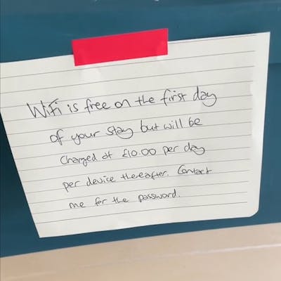 Handwritten note that reads "WiFi is free on the first day of your stay but will be charged at £10.00 per day per device thereafter. Contact me for the password."