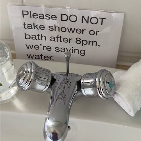 Sign that reads 'Please DO NOT take shower or bath after 8pm, we're saving water.'