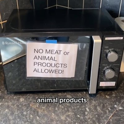 Sign that reads "NO MEAT or ANIMAL PRODUCTS ALLOWED!" taped to microwave