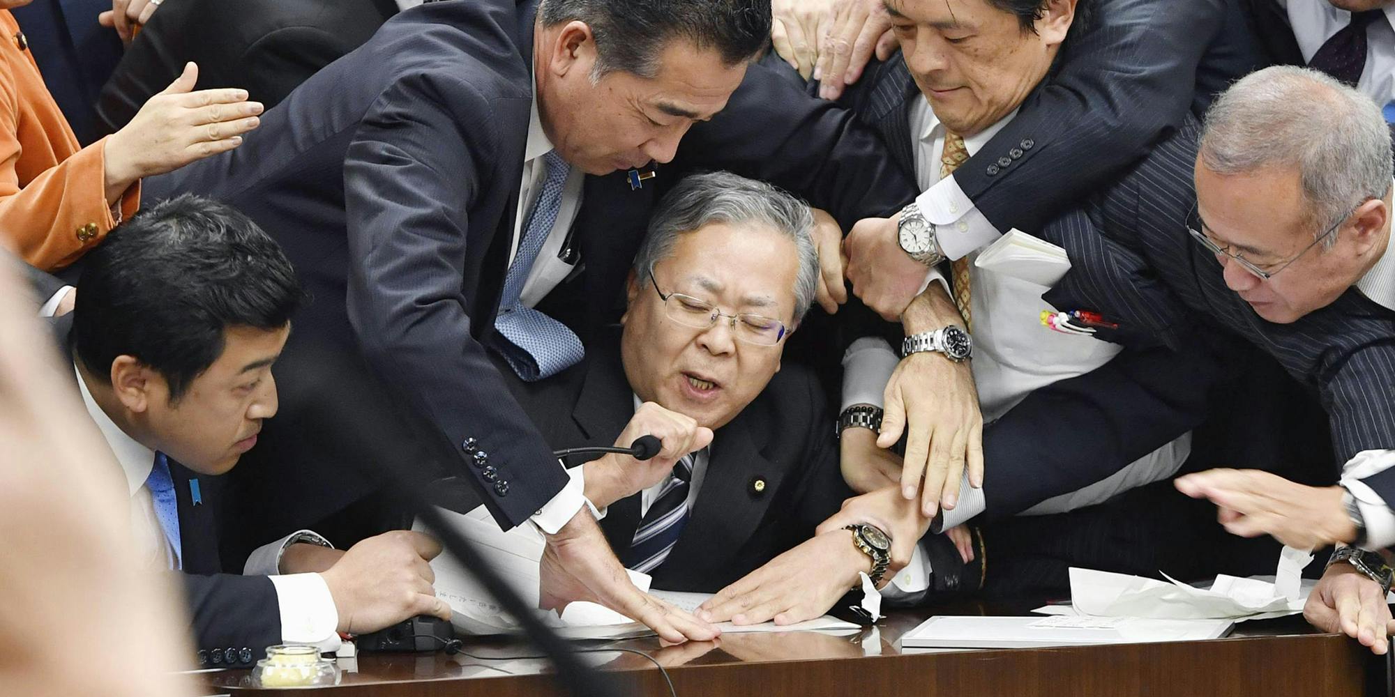 Japan's opposition parties' members try to stop Judicial Affairs Committee Chairman Shinichi Yokoyama, bottom center, from moving to hold a vote for a bill to revise an immigration control law