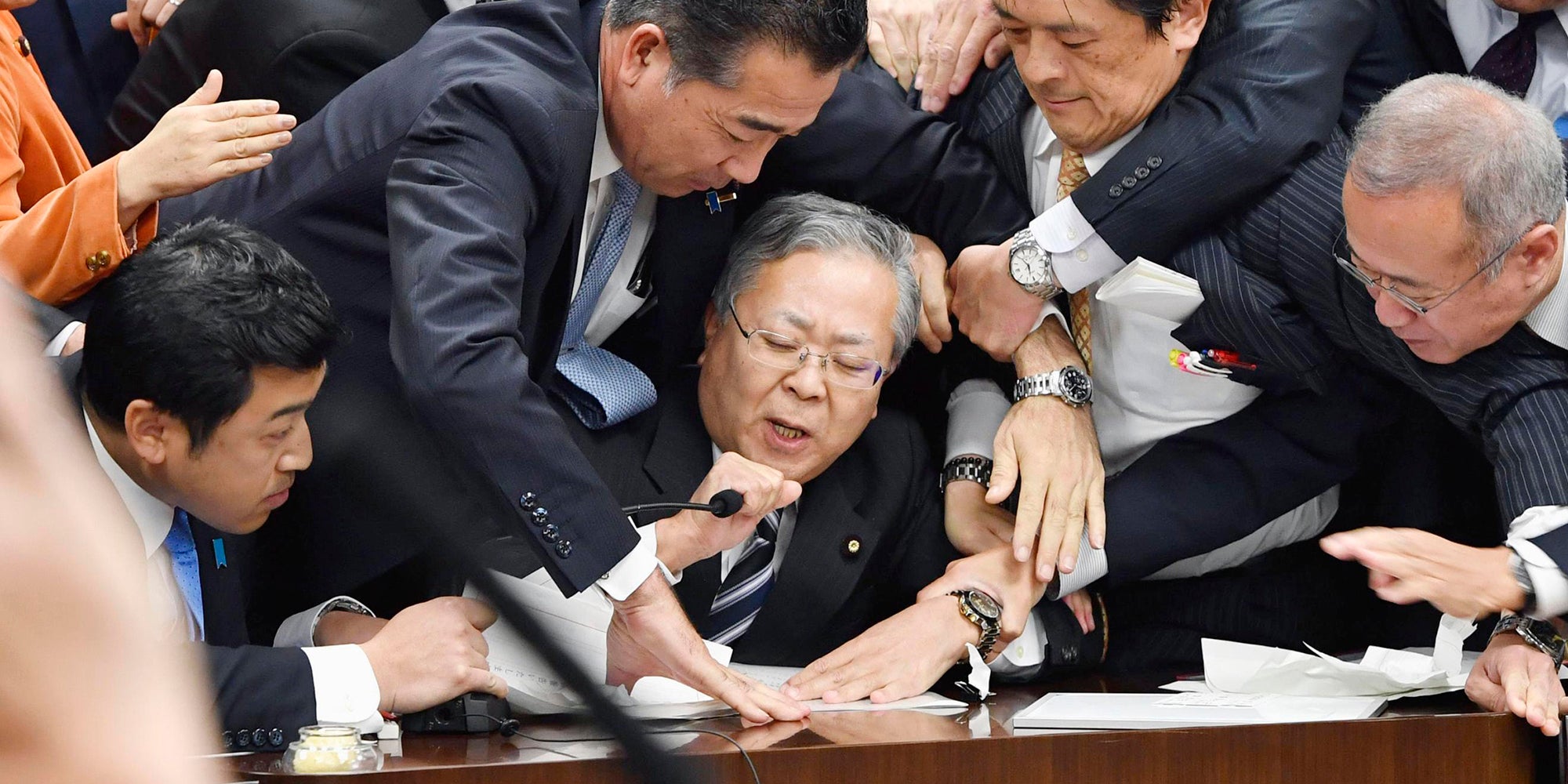 Japan's opposition parties' members try to stop Judicial Affairs Committee Chairman Shinichi Yokoyama, bottom center, from moving to hold a vote for a bill to revise an immigration control law